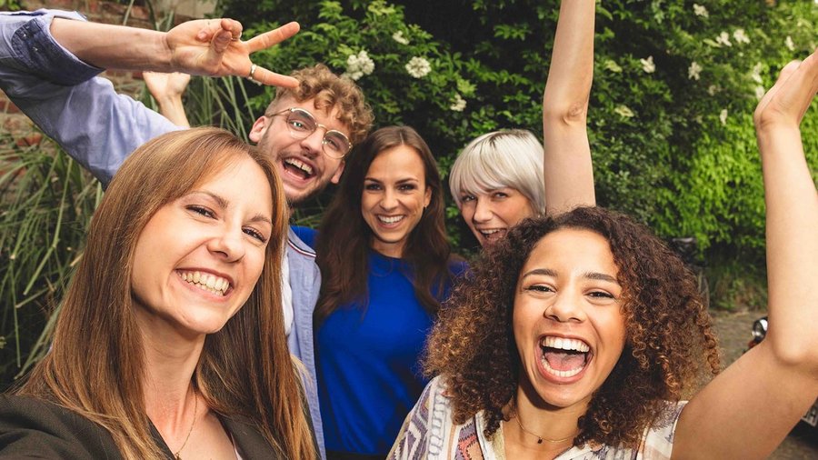 Plánování dovolené s přáteli – na co je potřeba se připravit Pět přátel stojících blízko sebe a smějících se do kamery